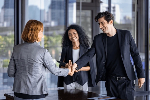 Dois profissionais em ambiente corporativo selando uma parceria com um aperto de mãos, simbolizando colaboração, confiança e oportunidades de carreira com a Genbyte.